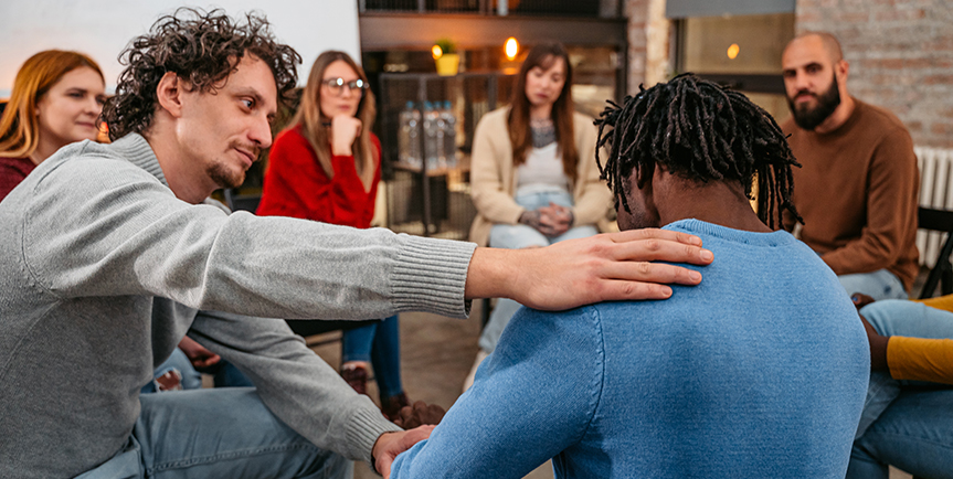 Man comforting another man during group therapy